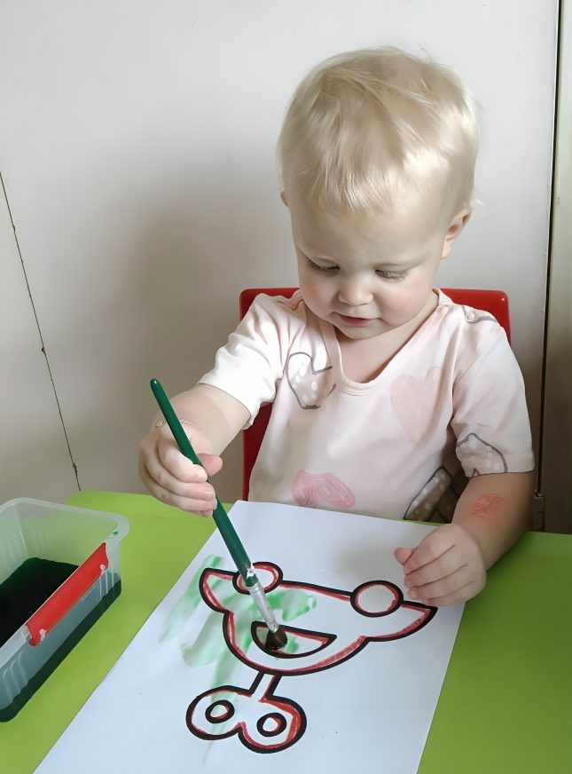 A toddler painting a picture at Toddies Preschool