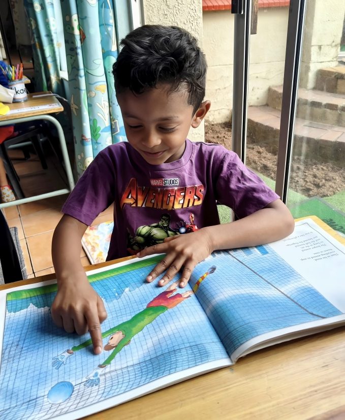 A boy reading a picture book at Toddies Preschool in Olivedale